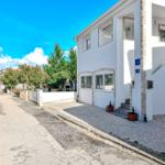 Weiße Villa mit Steinverkleidung und Terrasse. Eingangstreppe und Pflanzen vor dem Haus.