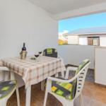 Terrasse mit Tisch, vier Stühlen und Wein. Blick auf Nachbarhaus.