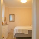 Schlafzimmer mit Bett, Kleiderschrank und Spiegel an der Wand.