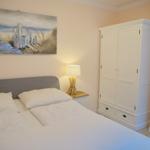 Schlafzimmer mit Bett, Kleiderschrank und Wandbild.