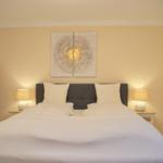 Schlafzimmer mit Doppelbett, Nachttischen und Wandbild.