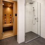 Dusche mit Glaswand und Sauna mit Holzwand