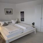 Schlafzimmer mit Doppelbett, Kleiderschrank und Wandbildern.