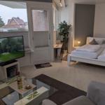 Wohnraum mit Schlafbereich, Fernseher und Blick auf Garten.