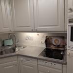 Küche mit weißen Schränken, Spüle, Herd und Mikrowelle.