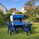 Garten mit blauem Tisch, vier Stühlen und Strandkorb.