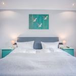 Schlafzimmer mit Bett, Nachttischen und Wandbild mit Möwen.