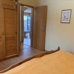 Schlafzimmer mit Holzbett, Schrank und Blick in Wohnbereich.