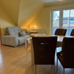 Wohn- und Essbereich mit Sofa, Tisch und Stühlen. Durchgang zur Dusche.