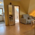 Wohnbereich mit Sofa, Kleiderschrank und Blick in die Küche und Bad.