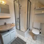 Badezimmer mit Dusche, Waschbecken und Toilette. Weiße Fliesen und Spiegel.