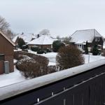 Schneebedeckte Häuser und Bäume vom Balkon aus gesehen.