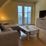 Wohnzimmer mit Sofa, Couchtisch und TV. Fenster zur Terrasse.