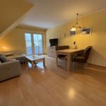 Wohn- und Essbereich mit Sofa, Esstisch und TV. Holzboden und gelbe Wände.