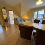 Wohn- und Essbereich mit Sofa, Tisch und Stühlen. Durchgang zur Küche und Bad.