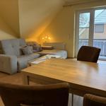 Wohn- und Essbereich mit Sofa, Tisch und Stühlen. Durchgang zur Terrasse.