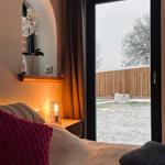 Schlafzimmer mit Blick auf verschneiten Garten. Bett, Nachttisch und Spiegel sichtbar.