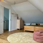 Zimmer mit Dachschrägen, Holzboden, Bett und runder Teppich.