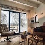 Wohnzimmer mit Sitzgelegenheiten, Tischen und Blick auf schneebedecktes Gelände.