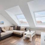 Wohnzimmer mit Ecksofa, zwei Dachfenstern und Holzboden.