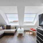 Wohnzimmer mit Dachschrägen, zwei Dachfenstern, Sofa, Couchtisch und Fernseher.