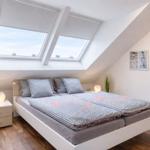 Schlafzimmer mit Dachschrägen, Doppelfenster und Bett mit Bettwäsche.