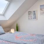 Schlafzimmer mit Dachschrägen, Dachfenster und Strandmotiven an den Wänden.
