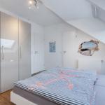 Schlafzimmer mit Dachschrägen, großem Bett und Schwebetüren. Wanddekoration mit Strandmotiv.
