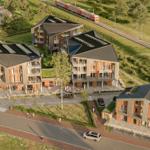 Moderne Wohnhäuser mit Balkonen und grünen Dächern in ländlicher Umgebung.