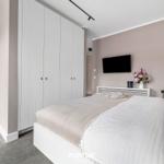 Schlafzimmer mit Bett, Kleiderschrank und Fernseher an der Wand.