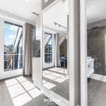 Badezimmer mit Dusche und Blick auf Terrasse mit Sitzgelegenheit.