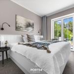 Schlafzimmer mit Bett, Wandbild und Fenster zum Balkon.