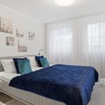 Schlafzimmer mit Bett, Vorhängen und Wandbildern.