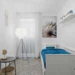 Schlafzimmer mit Bett, Fenster, Stehlampe und Wandbild.