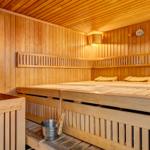 Sauna mit Holzbank, Thermometer und Eimer mit Besen