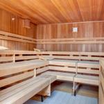 Holzsauna mit mehreren Sitzbänken und Temperaturanzeige an der Wand.