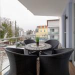 Terrasse mit Tisch und Stühlen, Blick auf schneebedeckte Bäume und Gebäude.