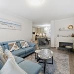 Wohnzimmer mit Sofa, Kamin und Blick in die Küche.