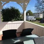 Terrasse mit Tisch und Stühlen, Blick auf Grün und Straße.