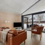 Wohnzimmer mit Ledersofa, TV und Blick auf verschneiten Garten.