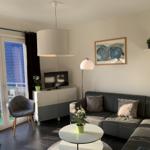 Wohnzimmer mit Sofa, Couchtisch und TV. Balkon mit Blick auf Dach.