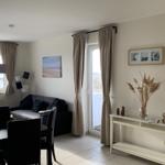 Wohnzimmer mit Sofa, Esstisch und Balkontür. Wandbild und Konsole mit Dekoration.