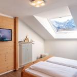 Schlafzimmer mit Dachfenster und TV an Holzwand.