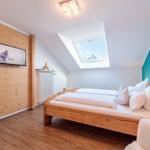 Schlafzimmer mit Dachfenster, Holzbett und Wandfernseher.