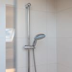 Dusche mit Handbrause und Glaswand in moderner Badewanne.