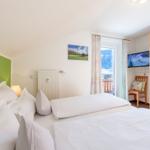 Schlafzimmer mit Doppelbett, Fenster und Holzschrank.
