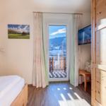Schlafzimmer mit Balkon, TV und Holzmöbel.