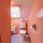 Badezimmer mit Toilette, Waschbecken und Dachfenster mit Vorhängen.