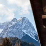 Schneebedeckte Berge sind durch ein Holzfenster sichtbar.
