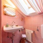 Badezimmer mit Waschbecken, Spiegel und Dusche unter Dach